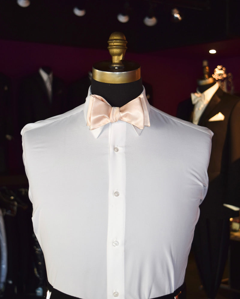White dress shirt with a nude color "self-tie" bow tie on a mannequin against a dark background