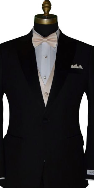 black tuxedo with a white tuxedo shirt wearing a champagne "pre-tied" bowtie and champagne vest against a white background