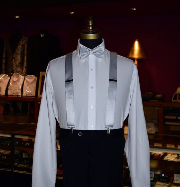 mannequin wearing a white tuxedo shirt with a silver pre-tied bowtie and silver suspenders inside a tuxedo shop as the background