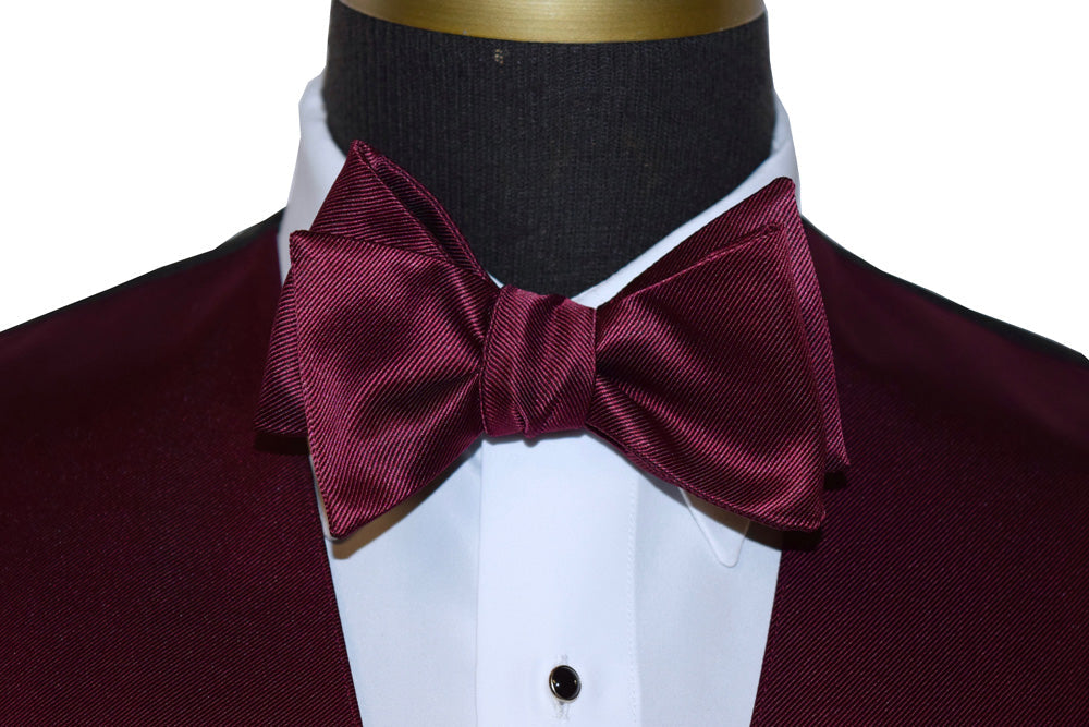 close-up front view Wine "tie-yourself" bow tie on a mannequin with a white shirt and black tuxedo jacket.