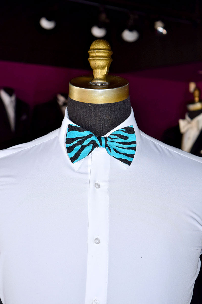 Mannequin wearing a white shirt with a blue and black zebra print bow tie against a blurred background.