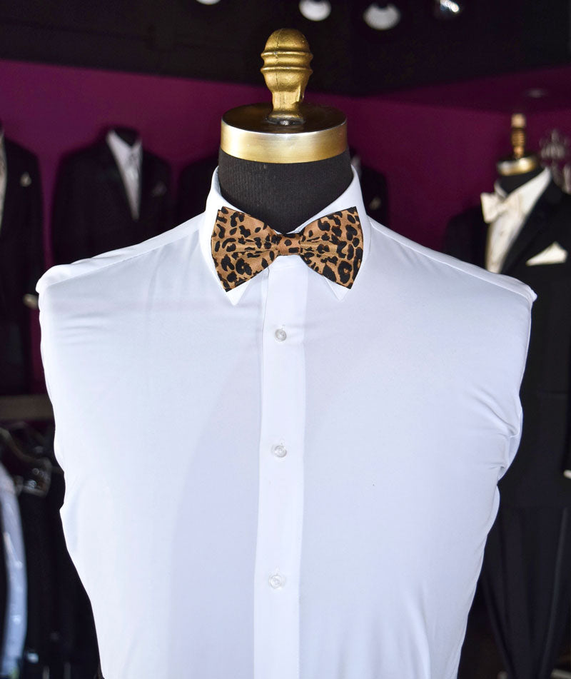 Mannequin wearing a white dress shirt with a leopard print bow tie against a wall with other tuxedos on display in a tuxedo shop