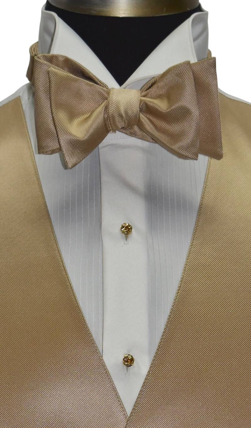 very close up of champagne "tie-yourself" bowtie shown with an ivory tuxedo shirt and vest against a white background