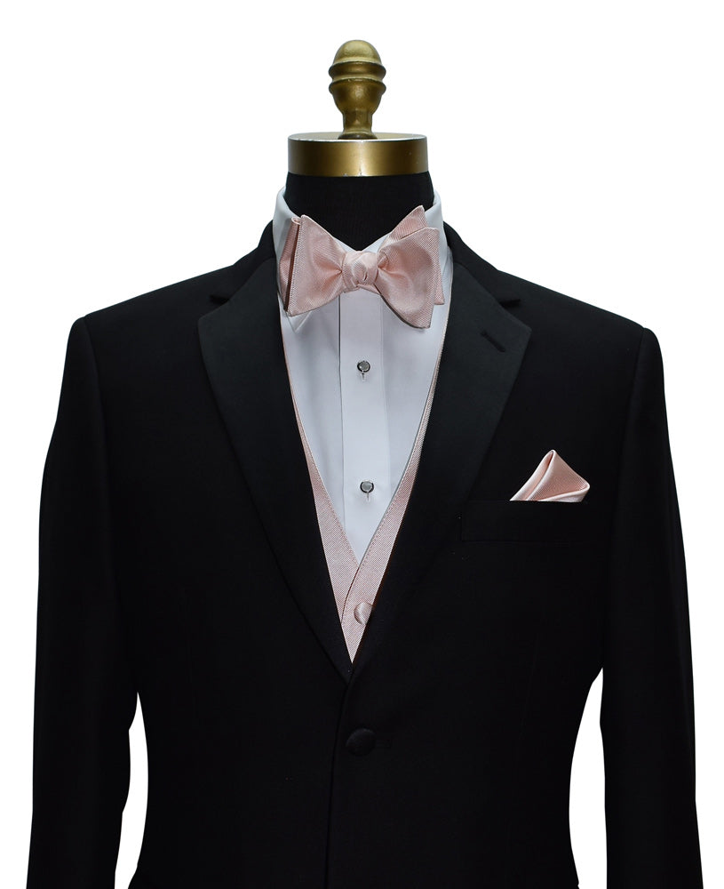 close-up Black tuxedo with blush "tie-yourself" bow tie and pocket square on a mannequin against a white background