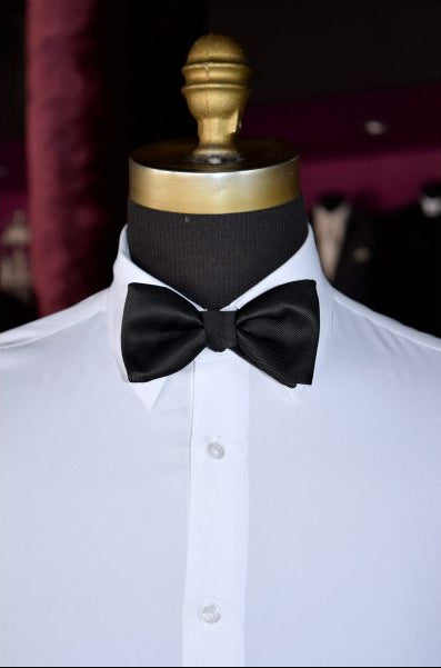 mannequin wearing a black bowtie and white tuxedo shirt on display in a tuxedo shop
