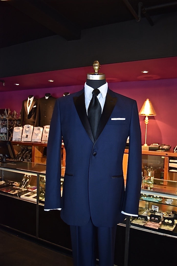 close-up Blue tuxedo on a mannequin with a white dress shirt and black silk necktie in a store setting 