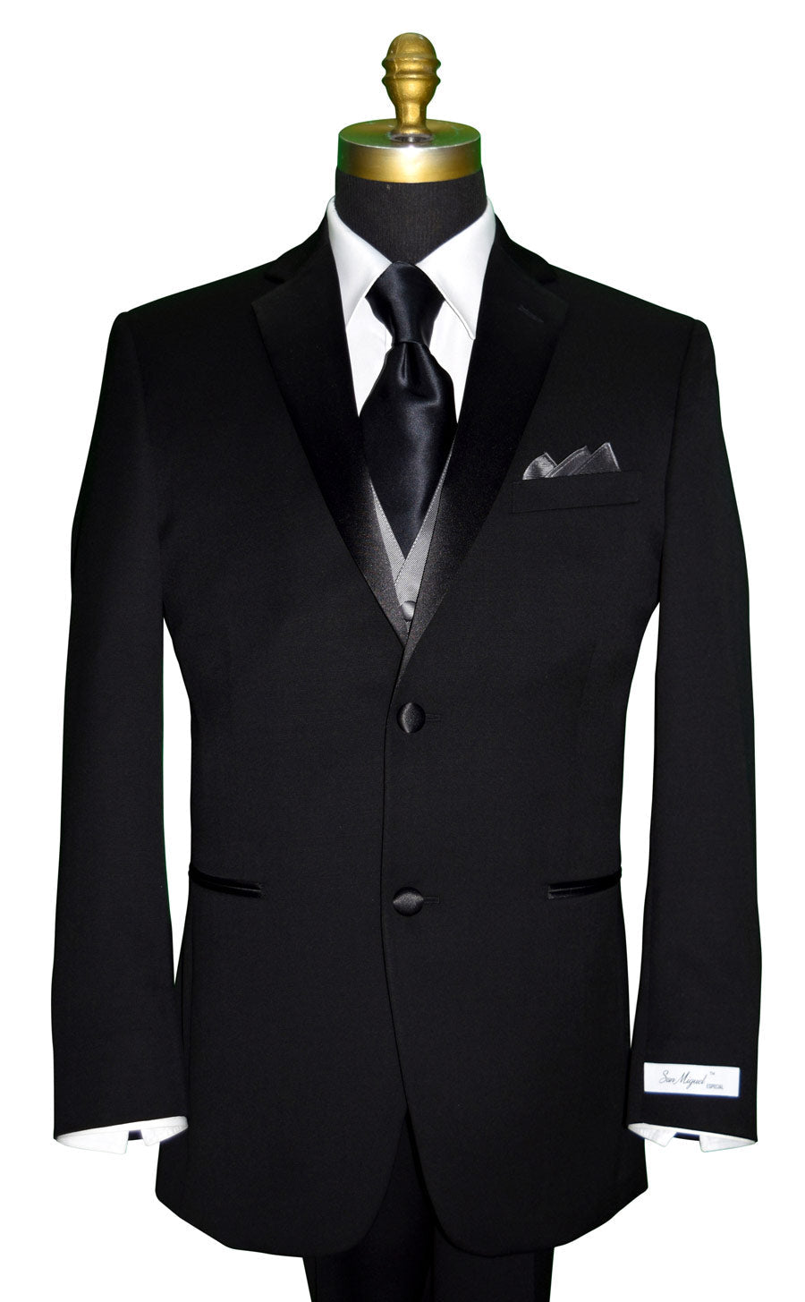 Mannequin wearing a black notch lapel tuxedo with a "San Miguel Especial" branded label with a gray vest and a black silk neck-tie against a white background