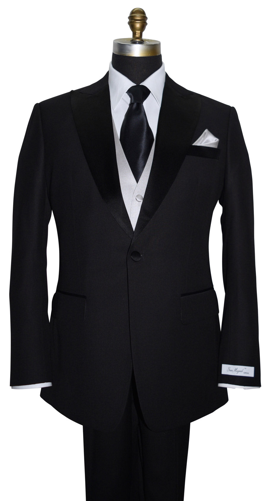 Black peak-lapel tuxedo with a "San Miguel Especial" branded label with white shirt and black silk necktie on a mannequin against a white background