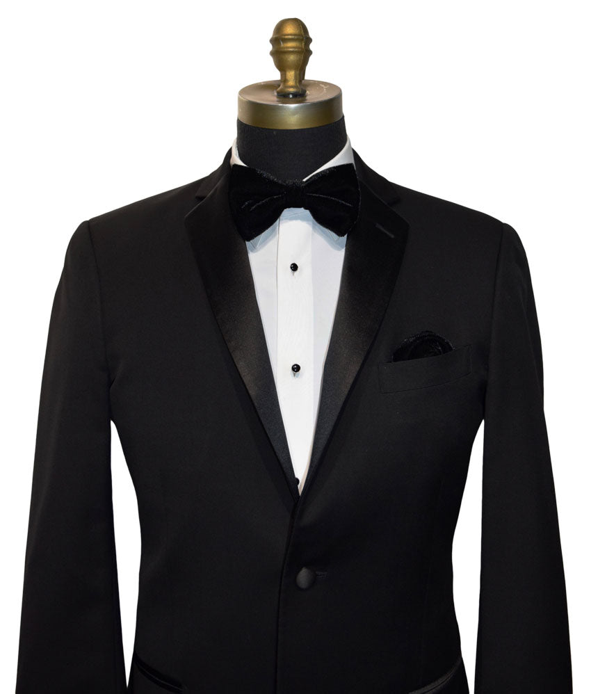 Black tuxedo with a black velvet bow tie on a mannequin against a white background