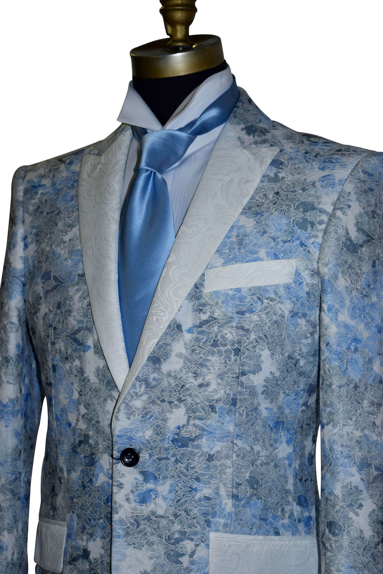 close-up Blue floral patterned tuxedo jacket on a mannequin with a long baby-blue necktie against a white background