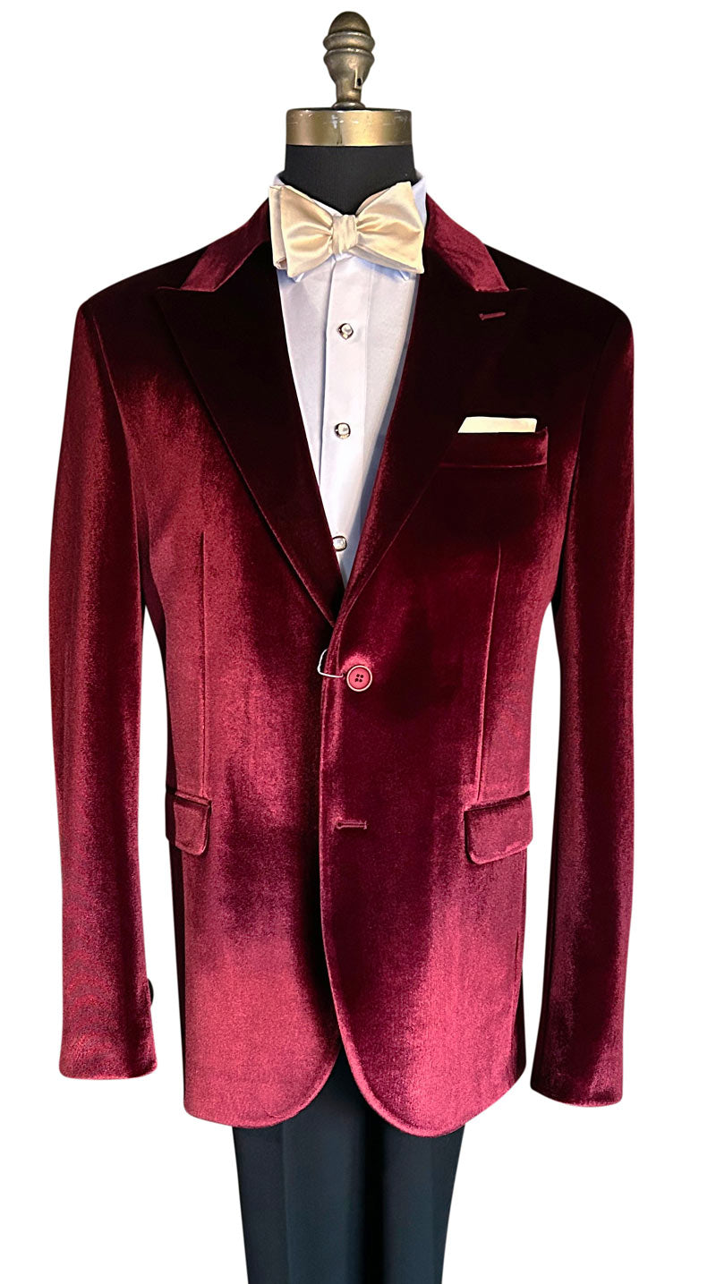 mannequin wearing a red burgundy velvet dinner jacket tuxedo with black pants and cream bowtie against a white background