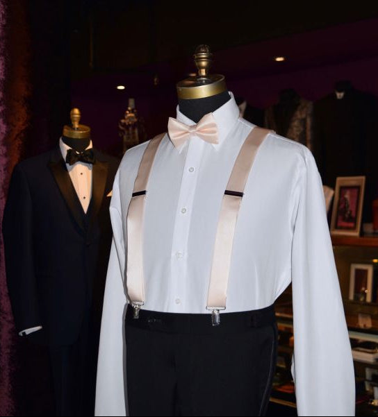mannequin wearing a white tuxedo shirt with nude color pre-tied bowtie and nude color suspenders inside a tuxedo shop