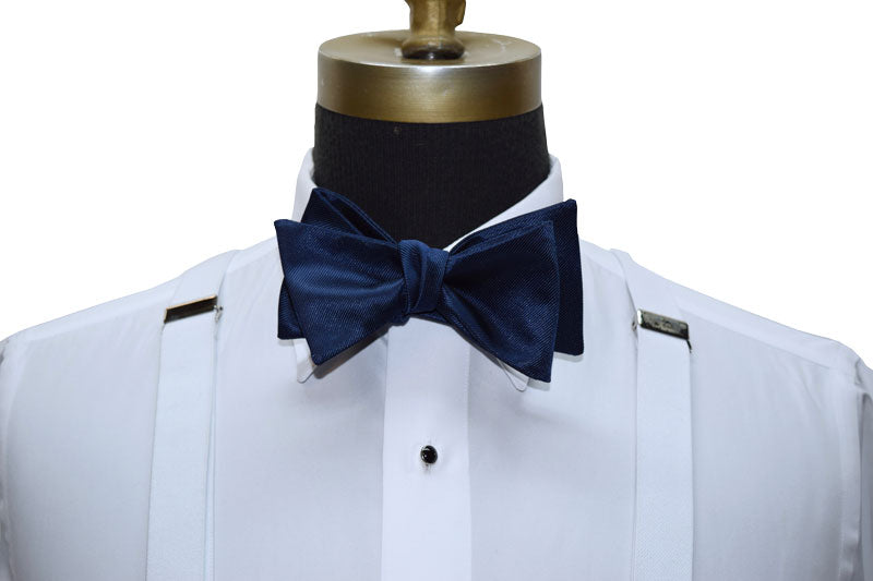 close-up mannequin wearing a white tuxedo shirt with a marine-blue tie-yourself bowtie against a white background