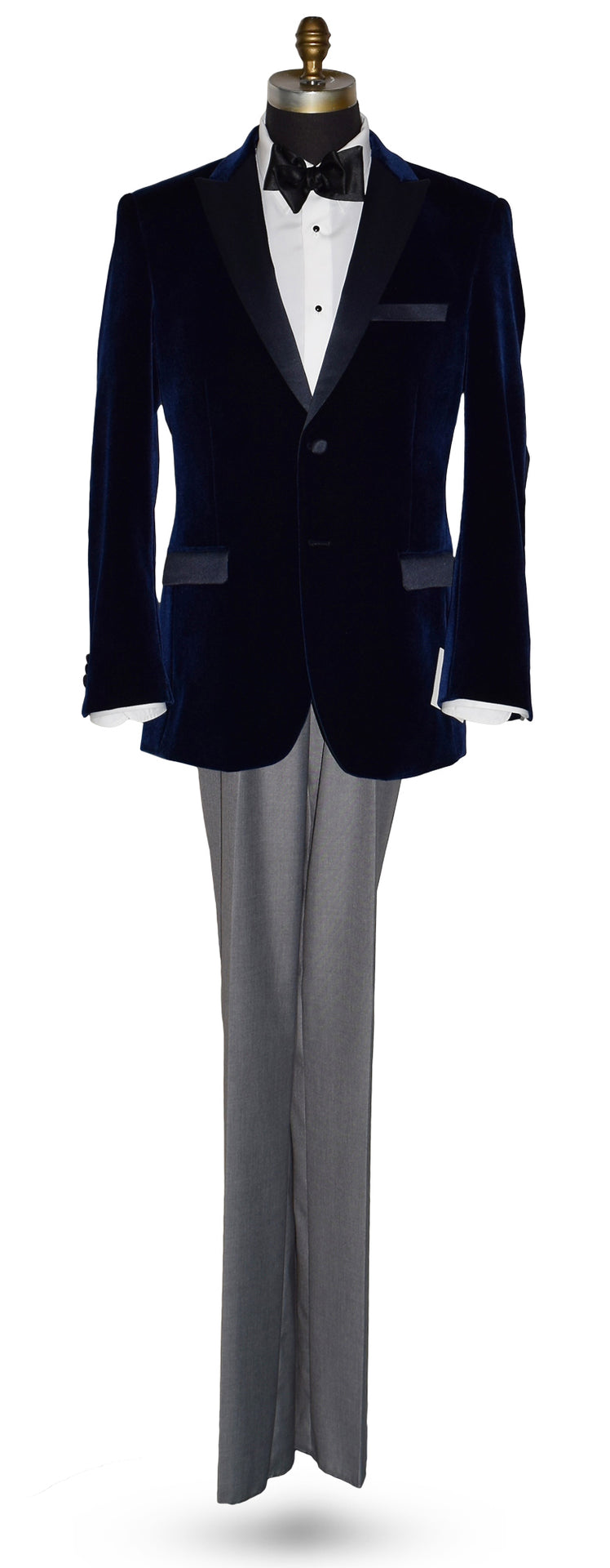 Navy velvet tuxedo with white tuxedo shirt and black satin bowtie with gray pants on a mannequin against a white background
