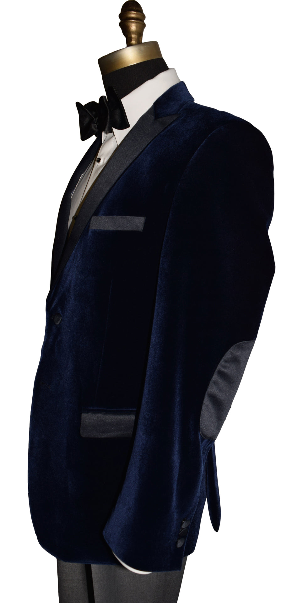 side view - Navy blue velvet tuxedo with elbow patches on a mannequin with a white shirt and black bow tie.