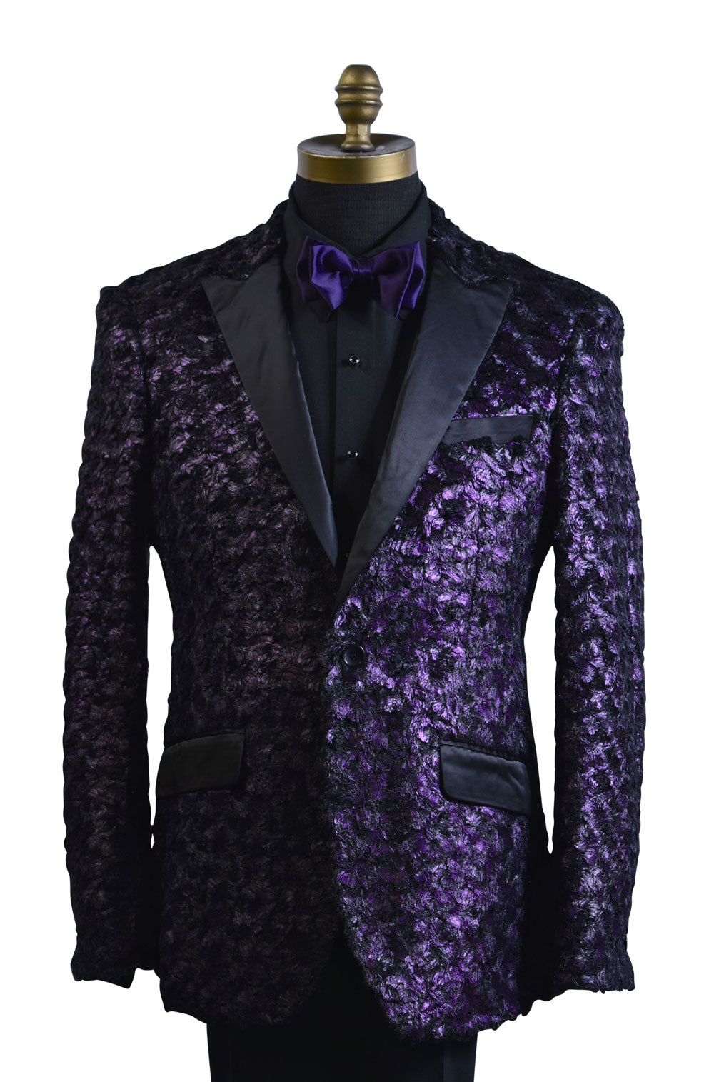 close-up life size mannequin wearing a purple tuxedo with black lapels with a black tuxedo shirt and purple bowtie against a white background