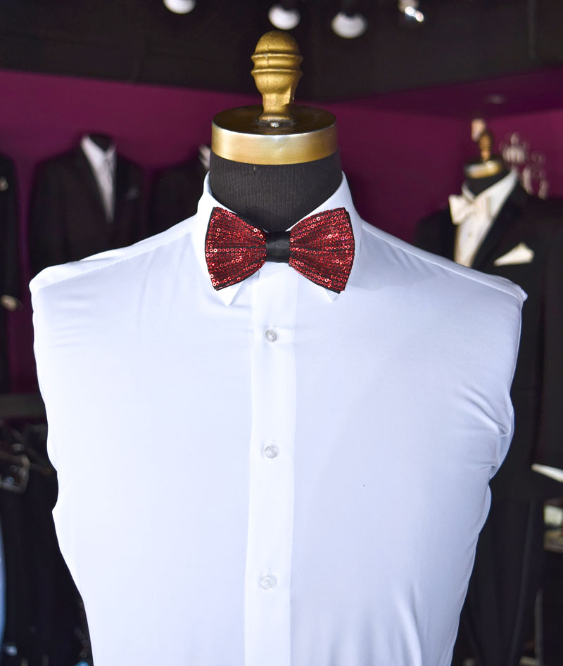 White dress shirt with a red sequin bow tie on a mannequin inside a tuxedo shop