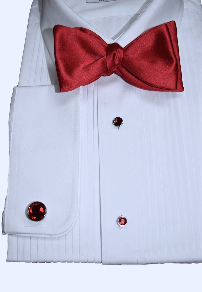 White dress shirt with a red bow tie and matching red tuxedo buttons and cufflinks on a white background