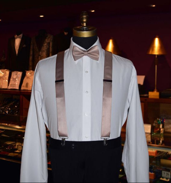 mannequin wearing a rose-gold "pre-tied" bowtie with rose-gold satin suspenders inside a tuxedo shop