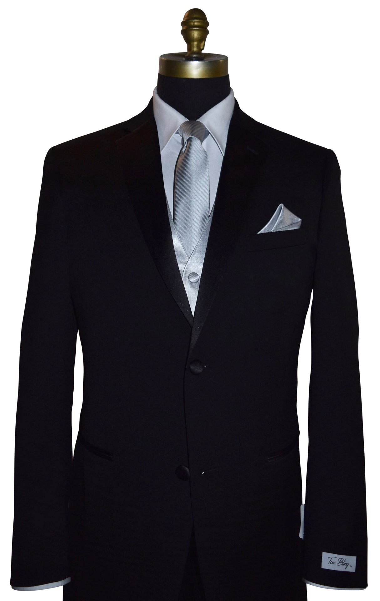 Black wedding suit with a "Tux Bling" branded label on the sleeve on a mannequin with a white shirt, silver necktie and silver vest, and pocket square.