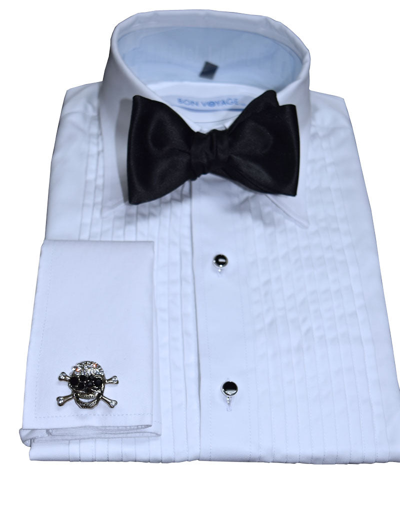 white tuxedo shirt wearing a black bowtie and "skull and crossbones" cufflinks against a white background