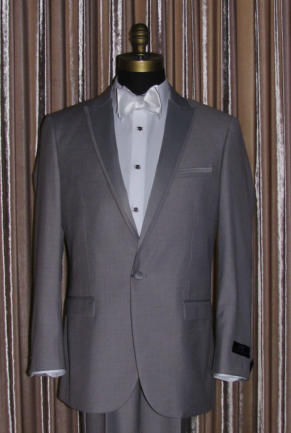 Gray tuxedo on a mannequin with a white shirt and white bowtie with "skull and bones" studs and cufflinks