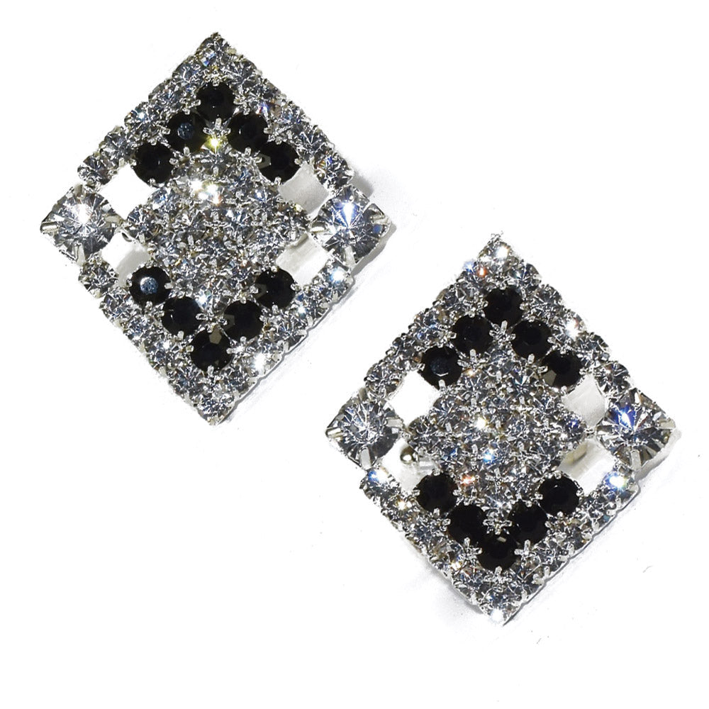 Pair of square-shaped cufflinks with black and clear gemstones on a white background