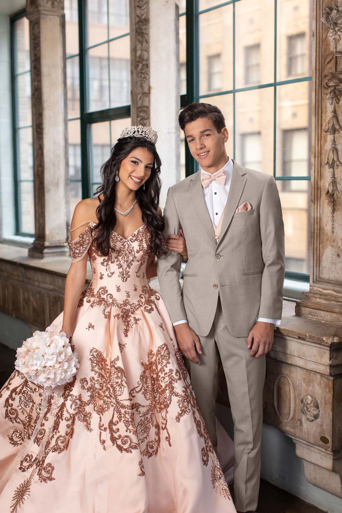 young hipanic man wearing a sand suit with pink bowtie  and young hispanic lady wearing a pink gown